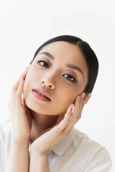 Junge asiatische Frau berühren Gesicht isoliert auf grau — Stockfoto