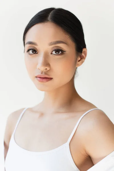 Asiatische Frau in weißen Kleidern blickt auf Kamera isoliert auf grau — Stockfoto