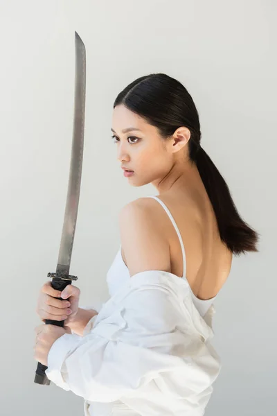 Hübsche Japanerin hält Wakizashi-Schwert isoliert auf grau — Stockfoto