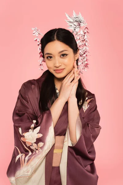 Souriant asiatique femme avec des bâtons de cheveux dans les cheveux en regardant caméra isolée sur rose — Photo de stock