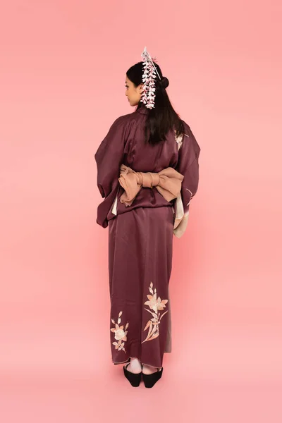Vue latérale de la femme asiatique en costume traditionnel sur fond rose — Photo de stock