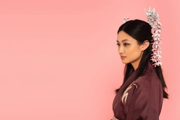 Young asian woman with hairsticks looking away isolated on pink — Stock Photo