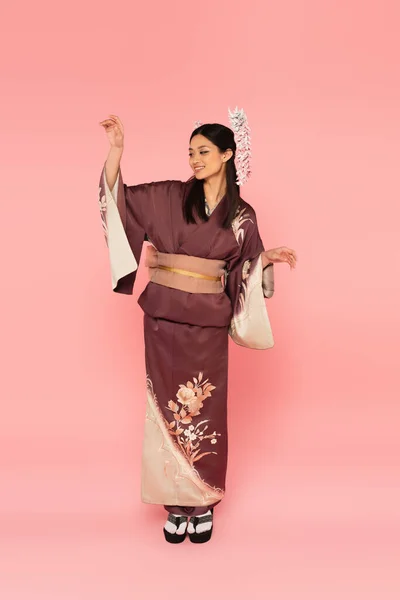 Full length of positive asian woman in oriental wear posing on pink background — Stock Photo