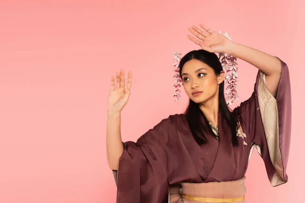 Junge Asiatin im Kimono und Kanzler im Haar isoliert auf rosa — Stockfoto