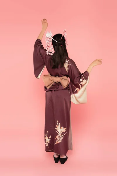 Visão traseira da mulher em quimono e kanzashi em pé sobre fundo rosa — Fotografia de Stock
