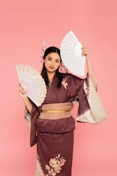 Asiática mujer en kimono holding fans aislado en rosa - foto de stock