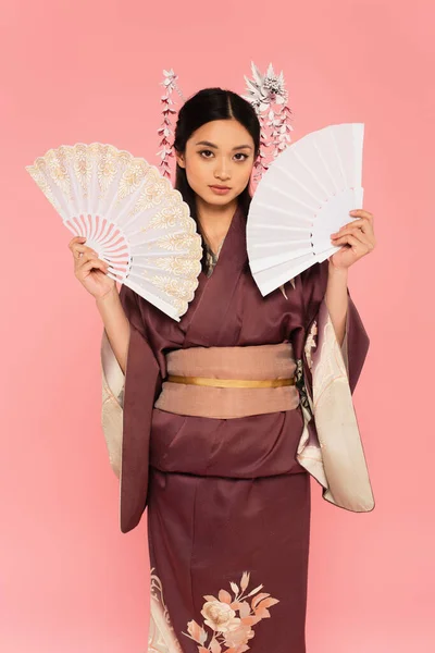 Japanese woman in kimono posing with fans isolated on pink — Stock Photo