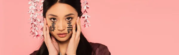 Portrait de femme asiatique avec hiéroglyphes de visage isolé sur rose, bannière — Photo de stock