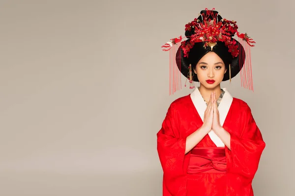 Азійка з червоними губами показує, що моляться руки ізольовані на сірих — стокове фото