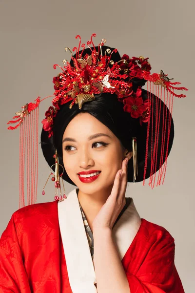 Улыбающаяся азиатка с традиционной прической, изолированная на сером — стоковое фото
