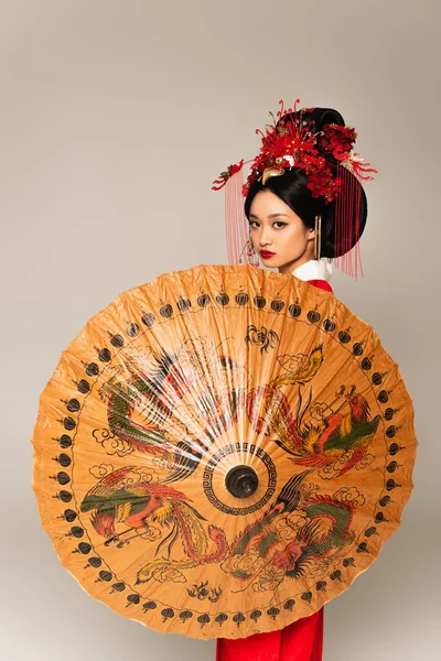Asian woman holding traditional umbrella isolated on grey — Stock Photo