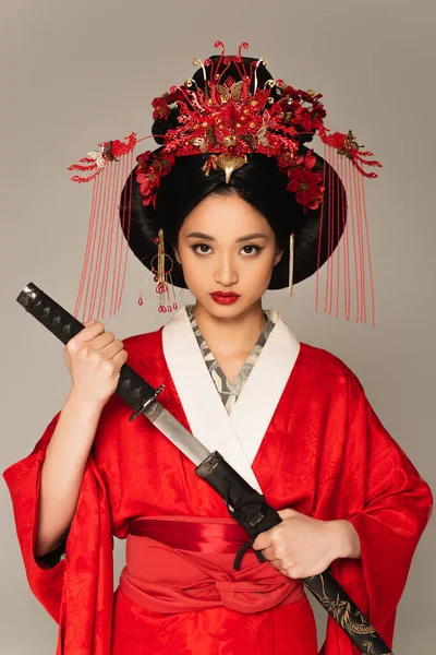 Femme asiatique en vêtements nationaux tenant l'arme isolée sur gris — Photo de stock