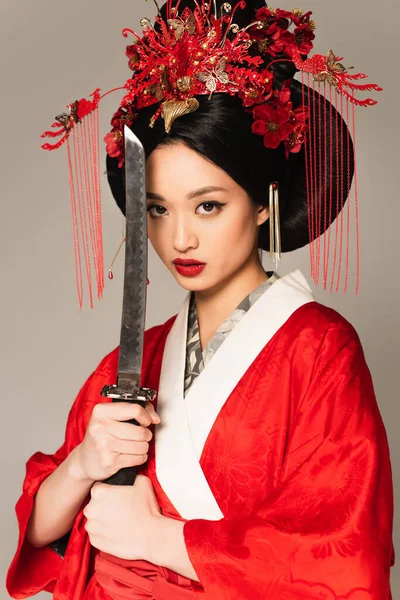 Morena mujer japonesa posando con espada aislada en gris - foto de stock