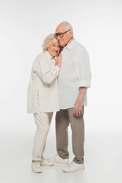 Elderly woman gently hugging senior man with hand on breast on white — Stock Photo