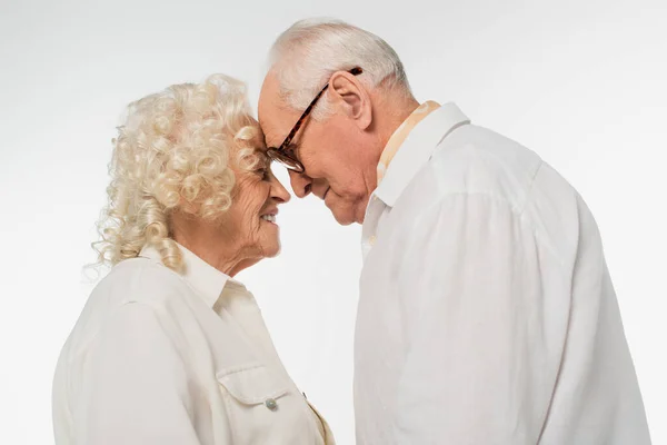 Coppia anziana delicatamente toccando con teste isolate su bianco — Foto stock