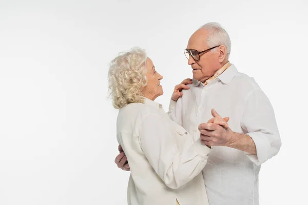 Pareja de ancianos en ropa casual bailando con las manos aisladas en blanco - foto de stock