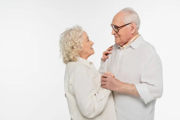 Pareja de ancianos en ropa casual mirándose con las manos aisladas en blanco - foto de stock