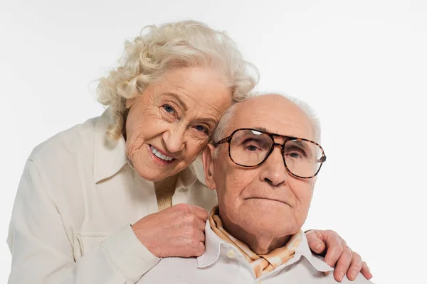 Felice coppia anziana abbracciare delicatamente e guardando la fotocamera isolata su bianco — Foto stock