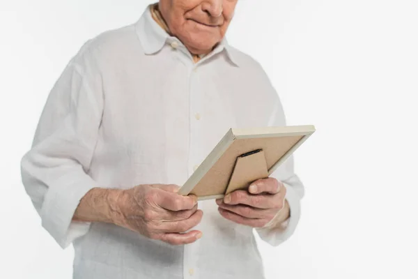 Partial view of elderly man in shirt holding photo frame in hands isolated on white — Stock Photo