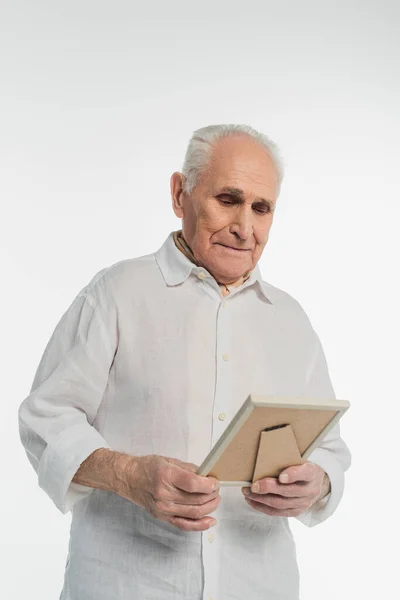 Upset elderly man in shirt holding photo frame in hands isolated on white — Stock Photo