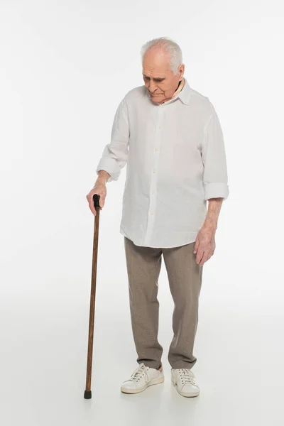 Trastornado anciano en ropa casual de pie con bastón en blanco - foto de stock