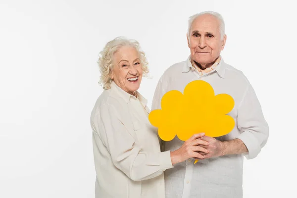 Sonriente pareja de ancianos sosteniendo amarillo burbuja de pensamiento y mirando a la cámara aislada en blanco - foto de stock