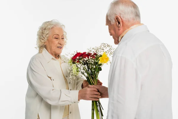 Elderly man presenting bouquet of flowers to wife isolated on white — Stock Photo