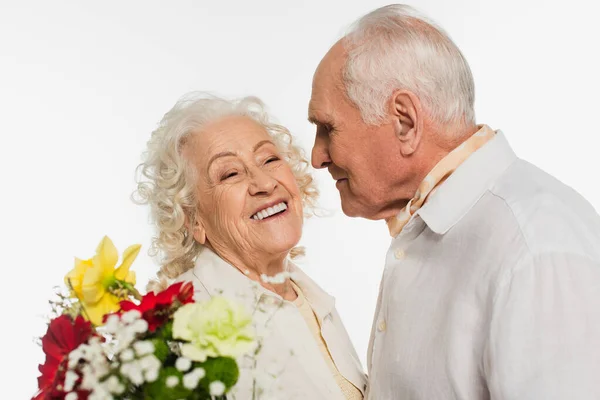 Glücklicher älterer Mann blickt lächelnde Frau mit Blumenstrauß auf weißem Grund an — Stockfoto