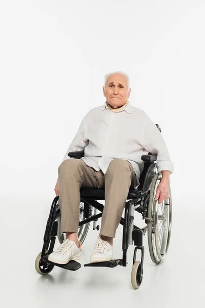 Homem idoso exausto em roupas casuais sentado em cadeira de rodas em branco — Stock Photo