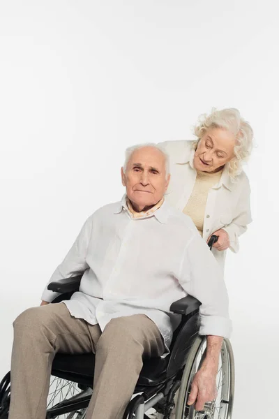 Femme âgée roulant en fauteuil roulant avec mari sur blanc — Photo de stock