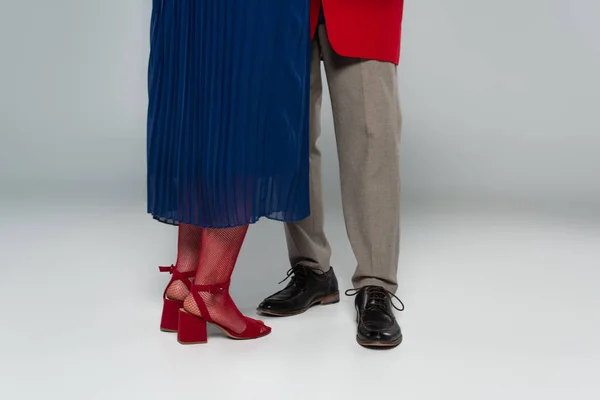 Частичный вид мужских и женских ног в стильной одежде, танцующих на сером — стоковое фото