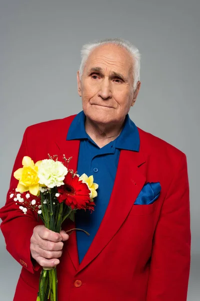 Homme âgé en vêtements élégants debout avec bouquet de fleurs isolé sur gris — Photo de stock