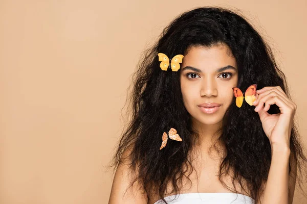 Young african american woman with orange butterflies on hair isolated on beige — Stock Photo