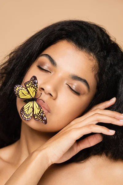 Young african american young woman with closed eyes and butterfly on lips isolated on beige — Stock Photo