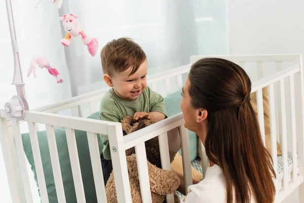 Glückliches Kind mit Spielzeug schaut Mutter zu Hause an — Stockfoto
