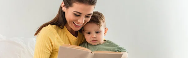 Jovem mãe e criança lendo livro perto de travesseiro em casa, banner — Fotografia de Stock