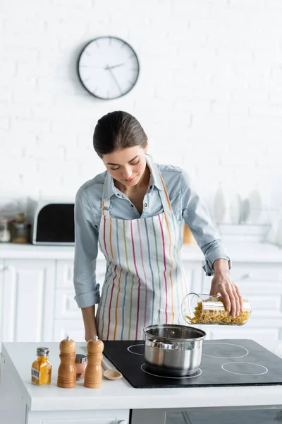 Молода жінка в фартусі готує макарони на кухні — стокове фото
