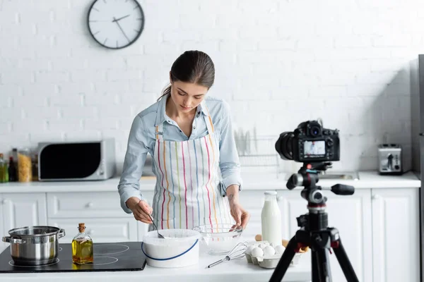 Blogueiro culinário perto de recipiente com farinha na frente de câmera digital borrada na cozinha — Fotografia de Stock