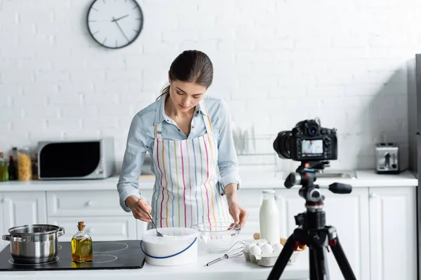 Blogger culinario cerca de contenedor con harina frente a cámara digital borrosa en la cocina - foto de stock