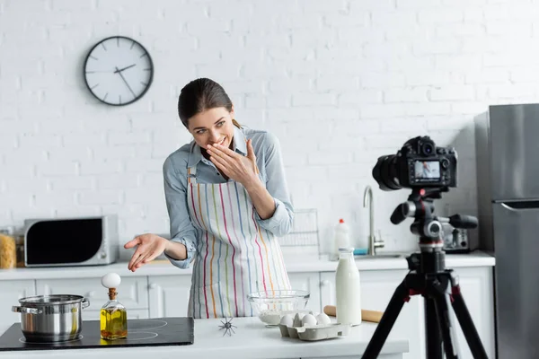 Lachender Kulinarik-Blogger zeigt vor verschwommener Digitalkamera auf Ei auf Flasche mit Öl — Stockfoto