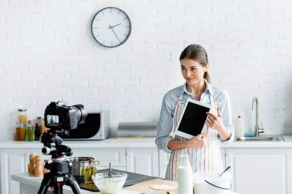 Kulinarische Bloggerin zeigt digitales Tablet mit leerem Bildschirm beim Online-Kochen in der Nähe der Digitalkamera — Stockfoto