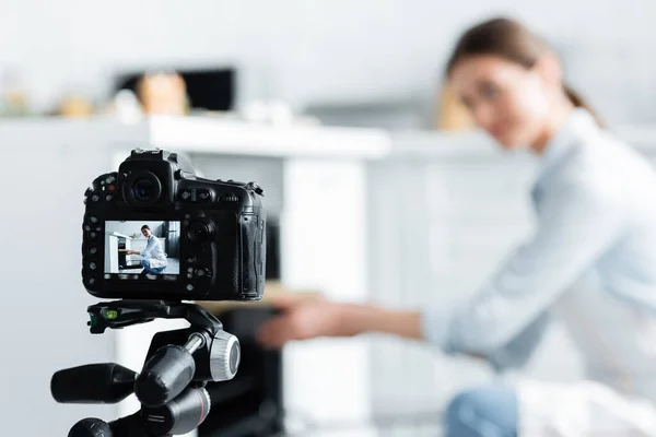 Selective focus of digital camera near culinary blogger placing baking form into oven — Stock Photo