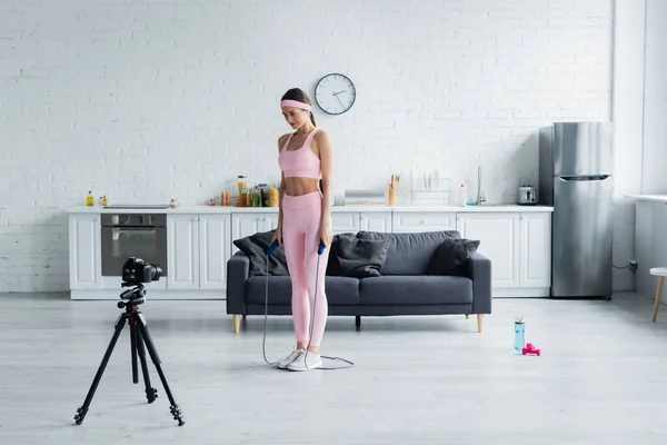 Sportive woman with jump rope recording lesson on digital camera at home — Stock Photo