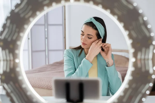 Blurred smartphone in holder with ring lamp near beauty blogger preparing for record — Stock Photo