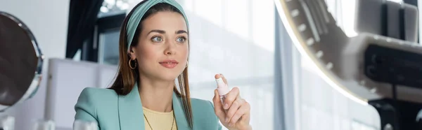 Young woman holding spray bottle of micellar water near ring lamp, banner — Stock Photo