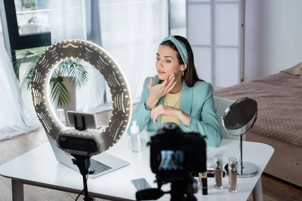 Pretty beauty blogger applying face foam near devices and ring lamp — Stock Photo