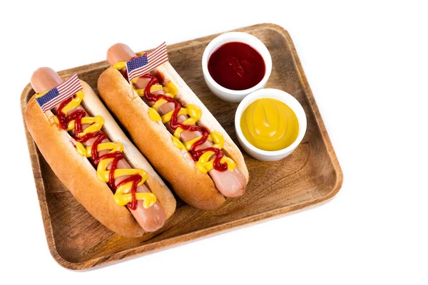 Bandeja de madeira com cachorros-quentes e tigelas com ketchup e mostarda isolada em branco — Fotografia de Stock