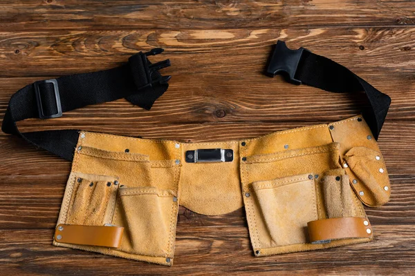 Vista superior del cinturón de herramientas de cuero en la superficie de madera, concepto de día de trabajo - foto de stock