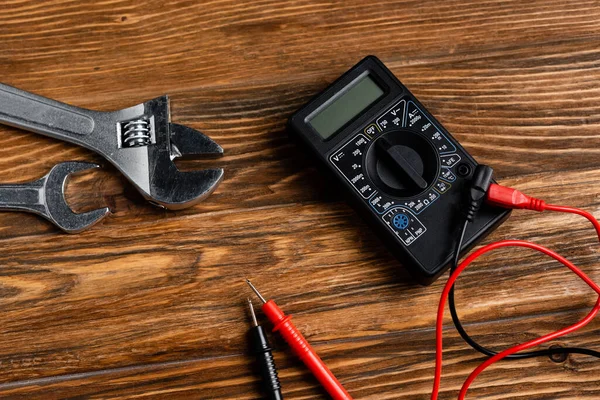 Top view of voltmeter and wrenches on wooden surface, labor day concept — Stock Photo