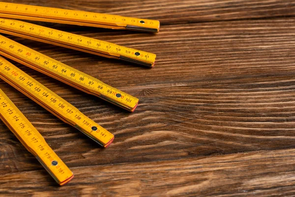 Règle pliante jaune sur la surface en bois, concept de jour de travail — Photo de stock